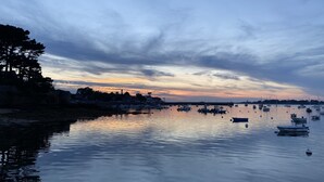 Ein ruhiger Hafen mit Booten und einer Stadt im Hintergrund bei Sonnenuntergang.