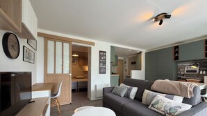 Ein modernes Wohnzimmer mit einem grauen Sofa, einem weißen runden Tisch und einem Holzbüro.