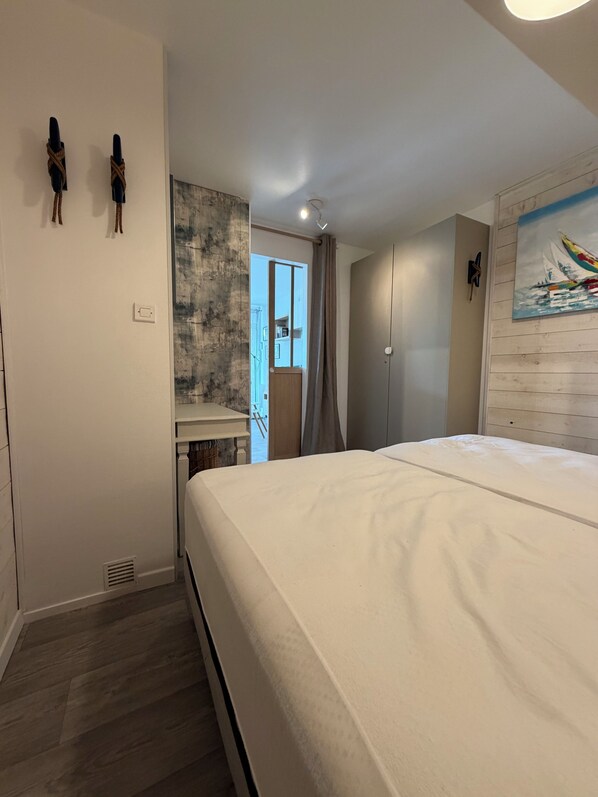 Un dormitorio con cama, escritorio y vistas al exterior.