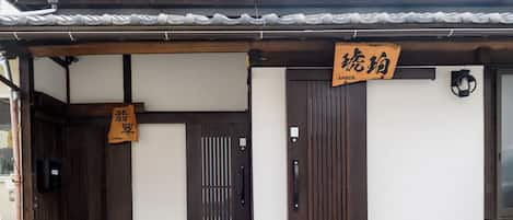 A traditional Japanese building with a tiled roof, wooden doors, and signage indicating a restaurant.