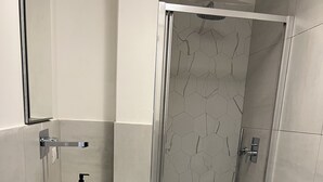 Uma casa de banho moderna com uma sanita, chuveiro e lavatório curvo.