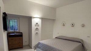 Quarto com cama, penteadeira, espelho e luminárias fixadas na parede.