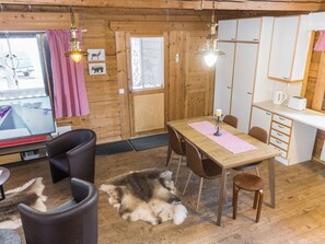 A cozy cabin interior with a dining area, wooden walls, and a large dog lying on the floor.