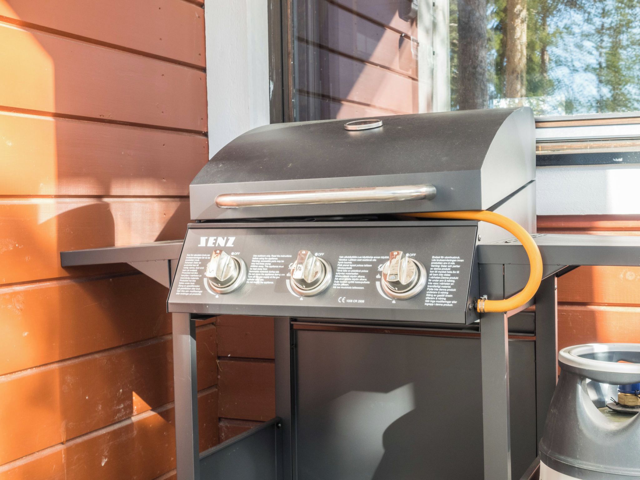 A black IENZ grill with three control knobs and a handle, mounted on a metal stand.