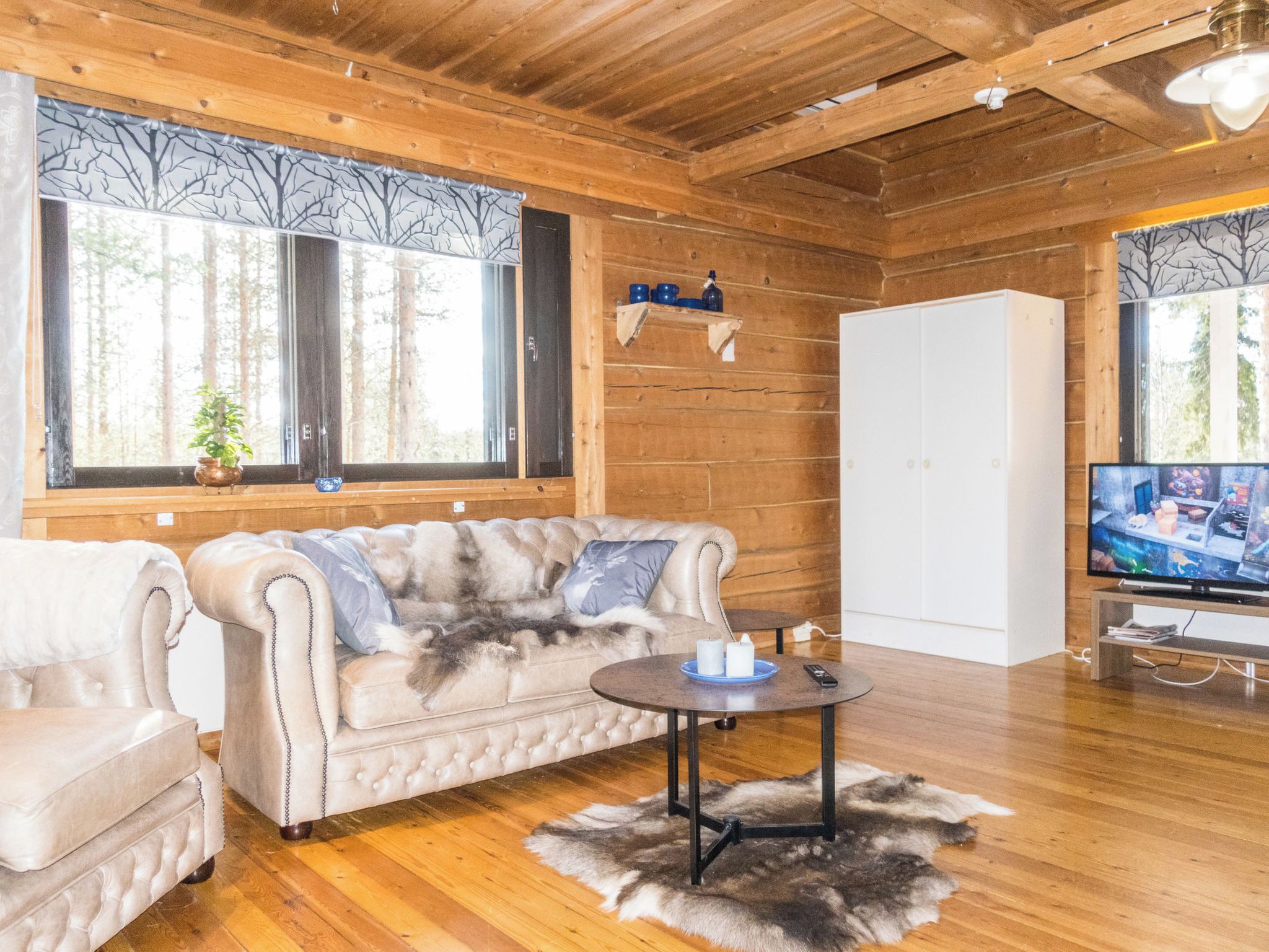 Una habitación acogedora con un sofá capitonado, una pequeña mesa redonda y un televisor.