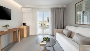 A modern living room with a sofa, a coffee table, a TV, and a balcony with curtains. - Oniro Skiathos (Skiathos)