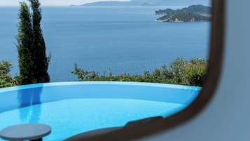 A view through a window of a pool with a clear blue sky and distant land.
