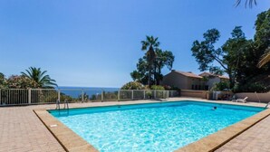 Una piscina rettangolare con acqua cristallina e azzurra, circondata da un solarium piastrellato.