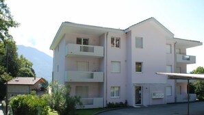 A multi-story building with balconies, a covered entrance, and a parking area. - Simona Fontile 22 by Interhome (Minusio)