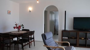 A living room with a dining table, chairs, a sofa, a TV, and a small cabinet. - Simona Fontile 22 by Interhome (Minusio)