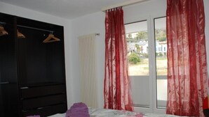 A bedroom with a bed, a wardrobe, and a window with curtains. - Simona Fontile 22 by Interhome (Minusio)