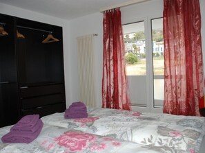 Ein Schlafzimmer mit einem Bett, einem Kleiderschrank und einem fenster mit Vorhängen.