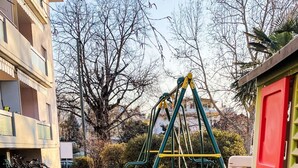 A playground with a red slide and a swing set in a grassy area. - Simona Fontile 22 by Interhome (Minusio)
