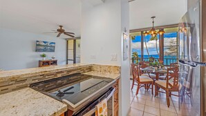 A modern kitchen with a large island, a dining area with a view, and a spacious balcony.