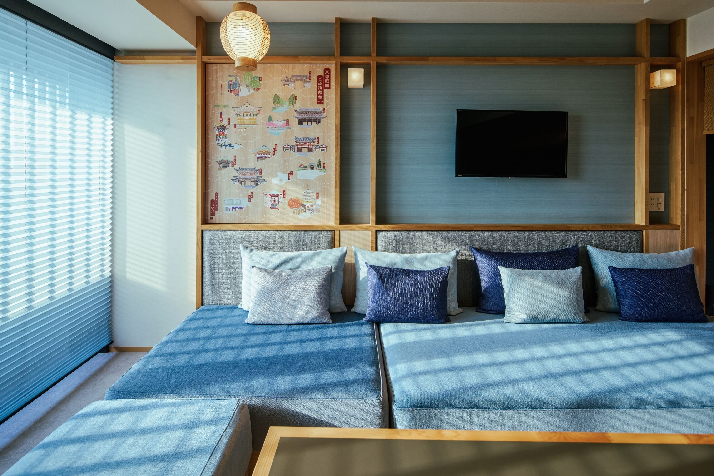 A modern room with a large bed, a mounted TV, and a traditional Japanese artwork on the wall.