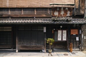 A traditional Japanese building with a tiled roof, wooden sliding doors, and a signboard.