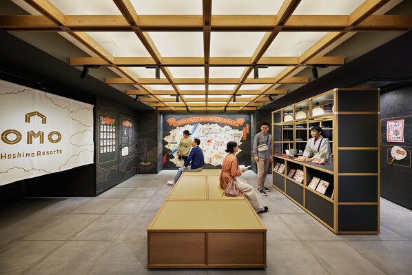 A hotel lobby with a wooden ceiling, a large map mural, and a reception desk with shelves of books and decorative items. - OMO5 Kyoto Gion by Hoshino Resorts (Kyoto)