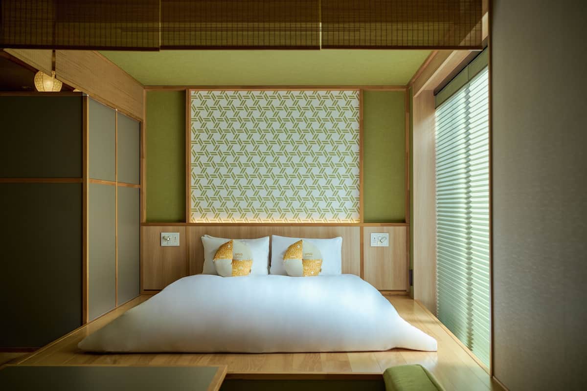 Une chambre de style japonais traditionnel, avec un sol recouvert de tatamis, un lit bas en bois et des paravents shoji.
