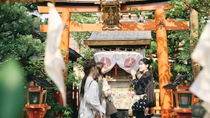 Un tradicional torii japonés con un santuario detrás, rodeado de vegetación exuberante.