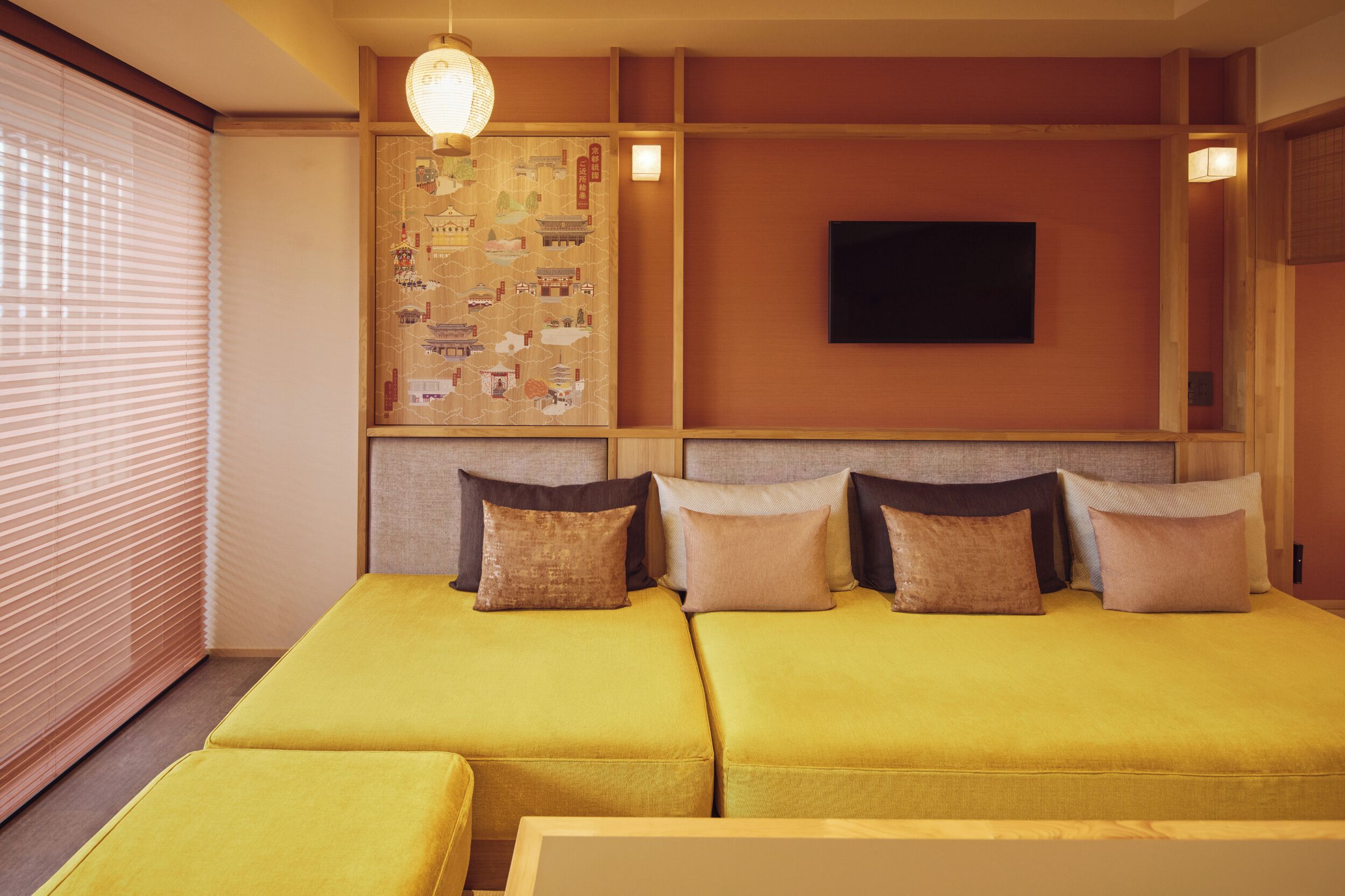 Habitación de hotel con dos camas, un televisor de pantalla plana, un panel decorativo en la pared y una ventana con persianas.