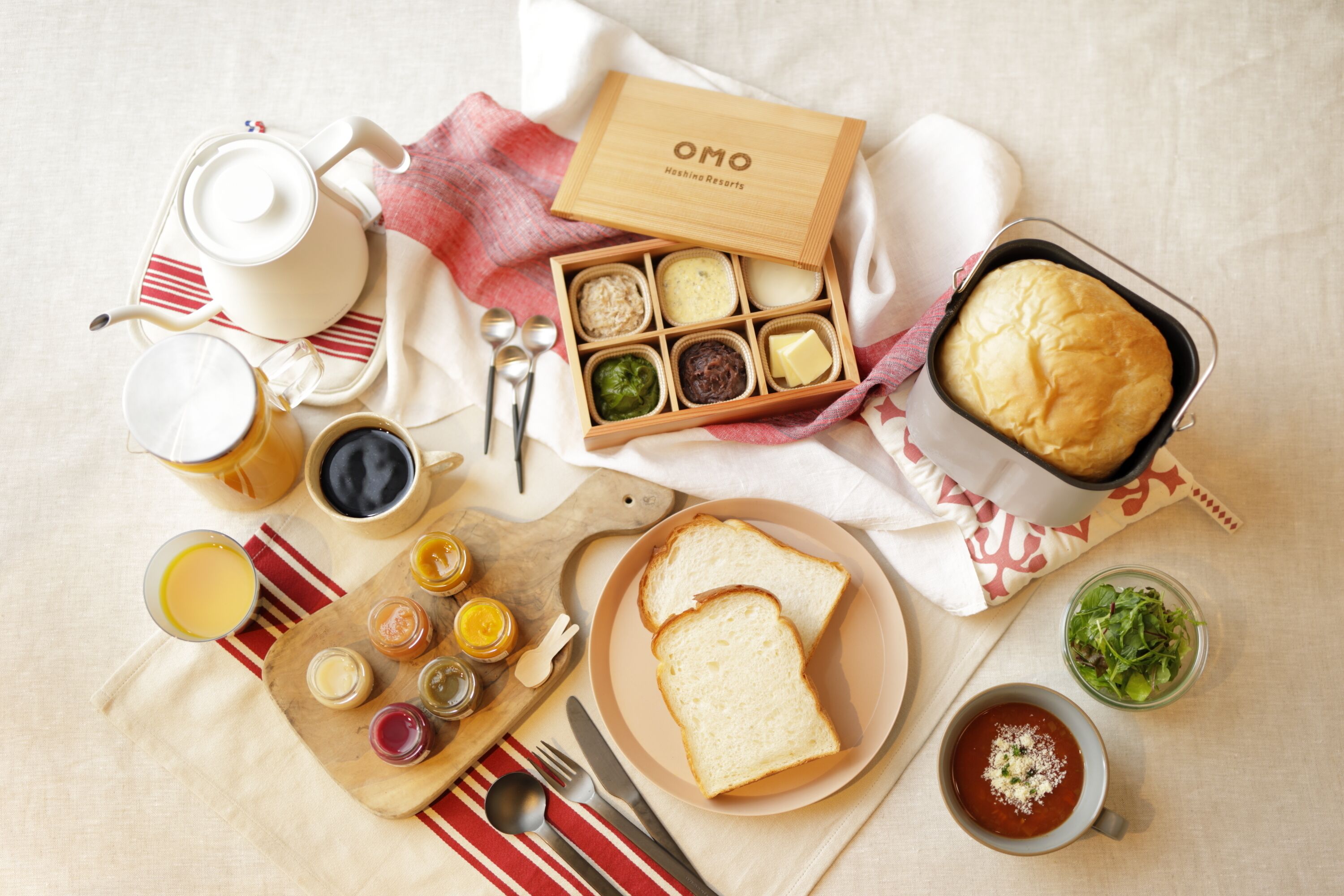 A breakfast setting with a variety of food items, including bread, eggs, and a muffin, arranged on a table with a checkered napkin and a wooden tray.