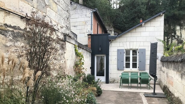 A narrow alleyway with a small building featuring a door and window, surrounded by greenery and a paved path. - La Tranquillité, atypical town house near Beauval and Châteaux de la Loire (Loches)