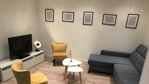 A modern living room with a flat-screen TV, two armchairs, a sofa, and a small round table. - La Tranquillité, atypical town house near Beauval and Châteaux de la Loire (Loches)