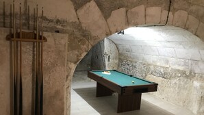 A pool table in a room with stone walls and a wooden rack holding pool cues. - La Tranquillité, atypical town house near Beauval and Châteaux de la Loire (Loches)