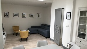 A modern living room with a grey sectional sofa, a yellow armchair, and a white dining table. - La Tranquillité, atypical town house near Beauval and Châteaux de la Loire (Loches)