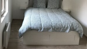A bedroom with a bed, two bedside tables, a window, and a wall-mounted heater. - La Tranquillité, atypical town house near Beauval and Châteaux de la Loire (Loches)