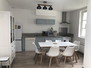 A modern kitchen with white cabinets, a dining table with chairs, and a built-in oven.