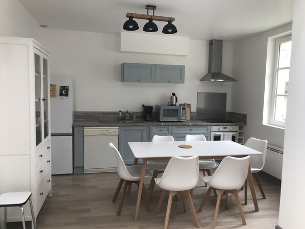 A modern kitchen with white cabinets, a dining table with chairs, and a built-in oven. - La Tranquillité, a unique townhouse near Beauval and the châteaux of the Loire Valley (Loches)