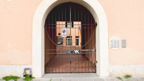 A gated entrance with a number sign, a no parking sign, and a fire alarm box.