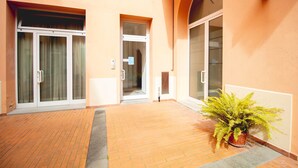 A building entrance with a potted plant, a door, and a wall-mounted light fixture.