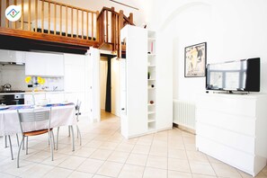 A modern kitchen with white cabinets, a dining table with chairs, and a staircase leading to an upper level.