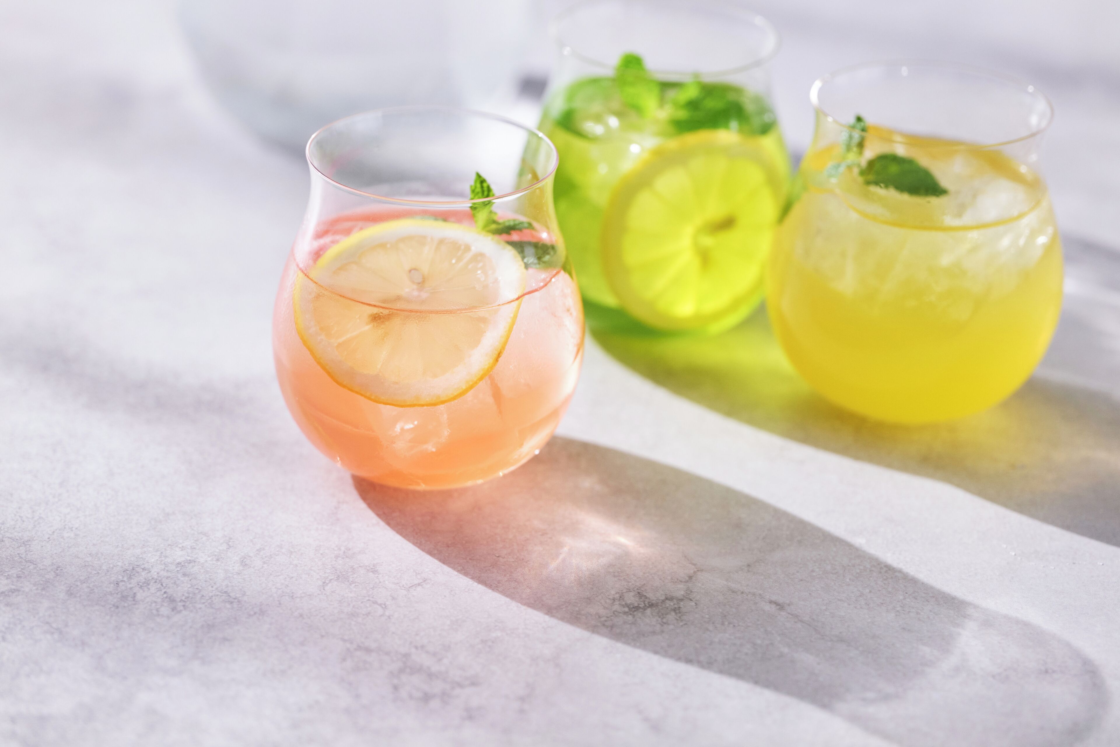 Três copos de bebidas com rodelas de limão e folhas de hortelã.