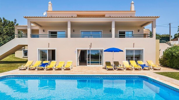 A two-story building with a swimming pool, multiple balconies, and sun loungers.