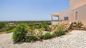 A modern building with a stone-paved entrance, a pool, and a view of the landscape.