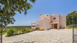 A modern house with a paved driveway, a small garden, and a view of the landscape.