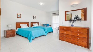Una habitación de hotel con dos camas, un tocador de madera, una mesita de noche y un espejo.