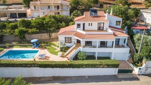 Una casa de varios pisos con piscina, un patio cubierto y una escalera que lleva al piso superior.