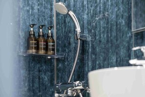 Een bad/douchecombinatie, een diep bad, designer toiletartikelen