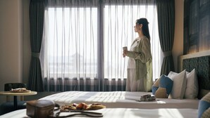 A hotel room with a bed, a small table with a cup, and a view of the outdoors through sheer curtains. - OMO3 Kyoto Toji by Hoshino Resorts (Kyoto)