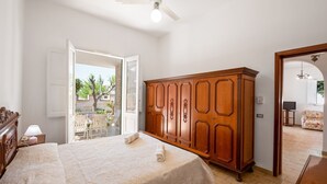 A bedroom with a bed, wooden wardrobe, and a door leading to a balcony. - Villa "Edy" near the Beach with Terrace & Garden (San Pietro in Bevagna)