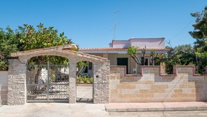 A house with a stone gate, a tiled roof, and a satellite dish. - Villa "Edy" near the Beach with Terrace & Garden (San Pietro in Bevagna)