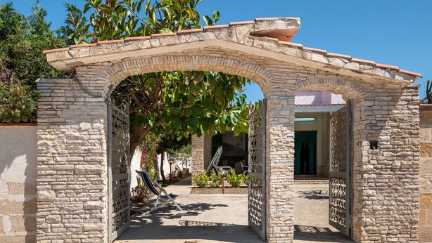 A stone archway leading to a courtyard with a view of a building. - Villa "Edy" near the Beach with Terrace & Garden (San Pietro in Bevagna)