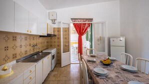 A kitchen with white cabinets, a sink, a refrigerator, and a dining table set with plates and glasses. - Villa "Edy" near the Beach with Terrace & Garden (San Pietro in Bevagna)