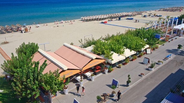 A beachside hotel with outdoor seating, a pool, and a view of the ocean.