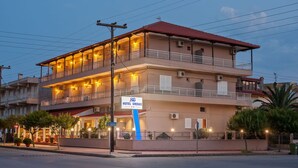 A two-story hotel with balconies and a sign indicating it is Hotel Grekas.