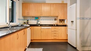 Une cuisine avec des meubles de rangement en bois, un réfrigérateur blanc, une cuisinière et un évier.